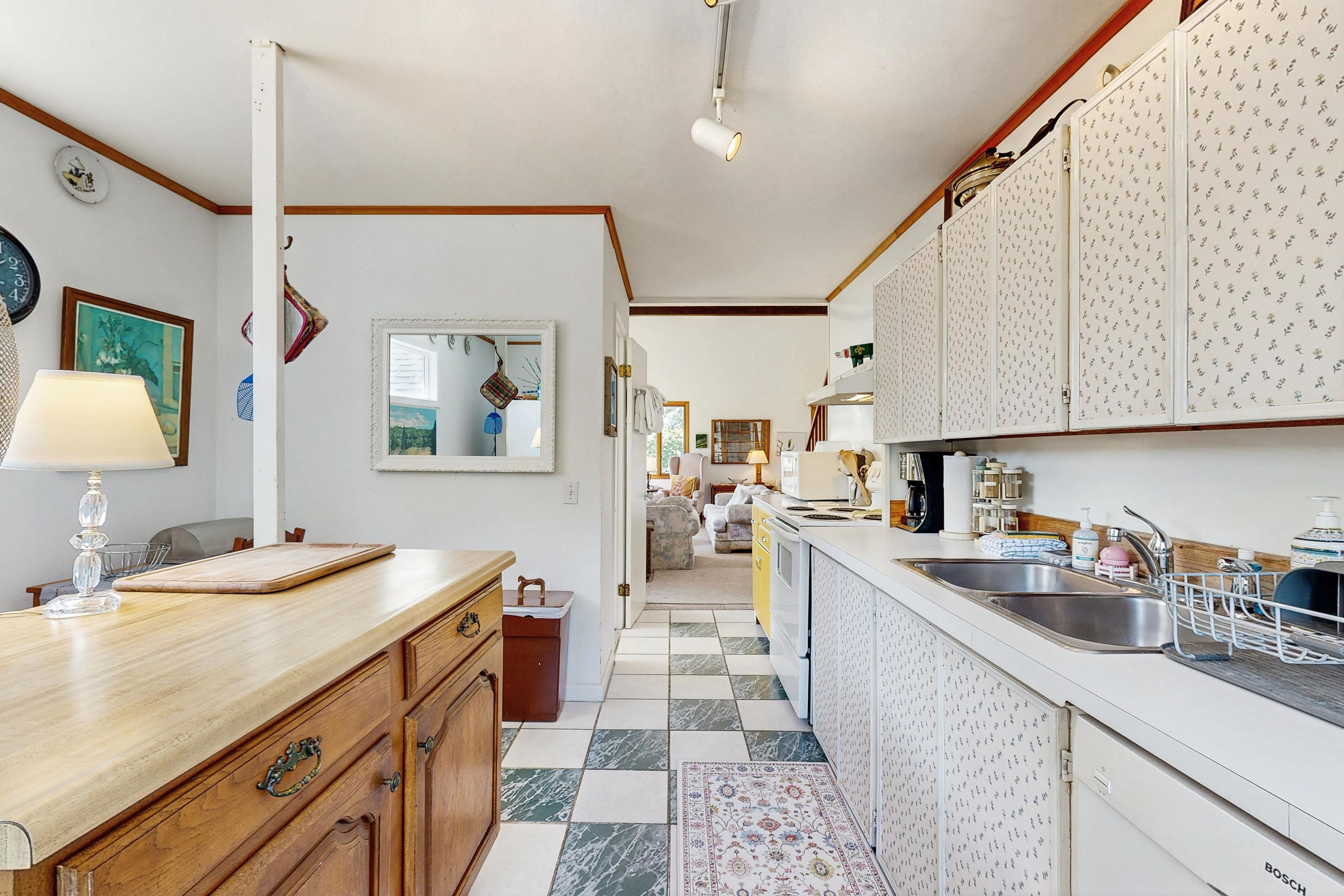 Une cuisine avec un carrelage à motifs, des placards en bois, un évier et un coin repas comprenant une table et des chaises.
