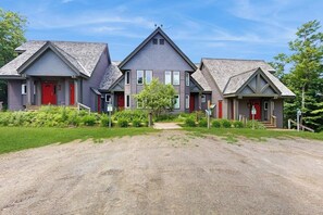 Eine Reihe von drei Häusern mit roten Türen, wobei das mittlere Haus ein dreieckiges Dach hat, und eine Auffahrt mit Kies.