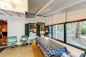 A room with a bed, a bench, a desk, and a large window with a view of trees. - Dog-Friendly Lakefront, w/Free WiFi, Patio, Deck/Dock, & Rustic Water Views (Charlotte)