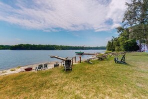 Blick auf einen See mit einer Anlegestelle, Stühlen und einem Boot.