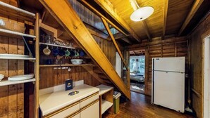 A wooden interior with a kitchen area, including a counter, shelves, and a refrigerator. - Dog-Friendly Lakefront, w/Free WiFi, Patio, Deck/Dock, & Rustic Water Views (Charlotte)