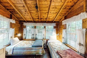 A cabin with two beds, wooden walls, and large windows. - Dog-Friendly Lakefront, w/Free WiFi, Patio, Deck/Dock, & Rustic Water Views (Charlotte)