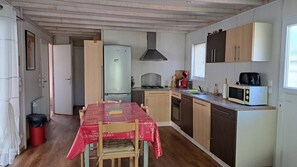 Eine kleine Küche mit Esstisch, Kühlschrank, Herd und Mikrowelle.