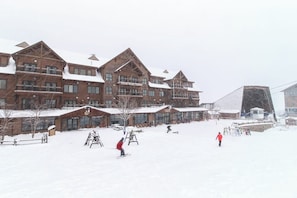 Ein großes Holzhaus mit mehreren Stockwerken und einer Skipiste davor.