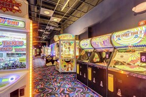 A row of arcade games with ticket redemption machines and colorful floor patterns. - Inviting riverfront home with hot tub on deck & fireplace, near skiing & golf (Montgomery)
