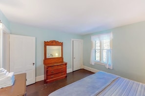 A bedroom with a bed, dresser, and two doors.