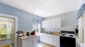 A kitchen with white cabinets, a black stove, and a window with blue curtains.