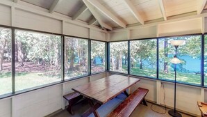 A room with large windows, a wooden bench, and a floor lamp.