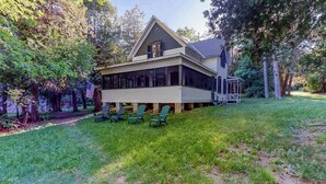 A house with a covered porch, a lawn, and several chairs.