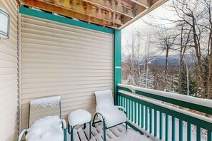 Eine überdachte Veranda mit Blick auf schneebedeckte Bäume und Berge.