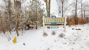 A snow-covered landscape with a sign for Kestrels Woods at North Hill and a yellow fire hydrant. - Spacious Mountain Retreat at Smugglers' Notch Resort w/ Great Views, Pool Access (Jeffersonville)
