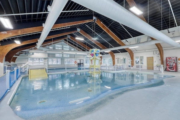 Ein Innenpool mit hoher Decke, Holzbalken und freiem Blick auf den Poolbereich.