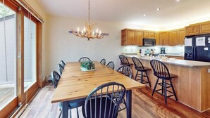 A modern kitchen with wooden cabinets, a central island, and a chandelier. - Inviting ski-in/ski-out condo - free WiFi, gas fireplace & free ski shuttle (Jay)