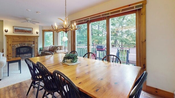 A dining area with a wooden table, chairs, a chandelier, and a fireplace. - Inviting ski-in/ski-out condo - free WiFi, gas fireplace & free ski shuttle (Jay)