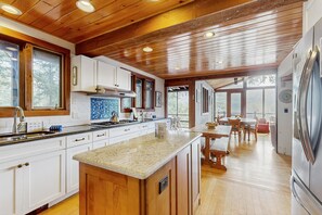 Eine moderne Küche mit Holzschränken, einer Granit-Arbeitsplatte und einem Edelstahl-Kühlschrank.
