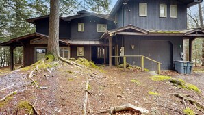 Een houten chalet met twee verdiepingen, een overdekte veranda en een garage.