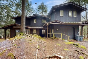 Eine zweigeschossige Holzhütte mit einer Laube und einer Garage.