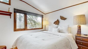 Een slaapkamer met een groot bed, een nachtkastje, een lamp en een raam met zonwering.