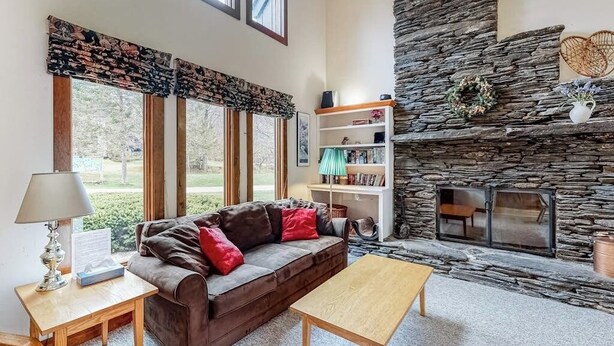 Una sala de estar con chimenea de piedra, un sofá, una mesa de centro y una estantería.