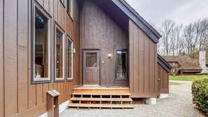 Un edificio moderno con fachada de madera, una puerta principal y escalones que conducen a la entrada.