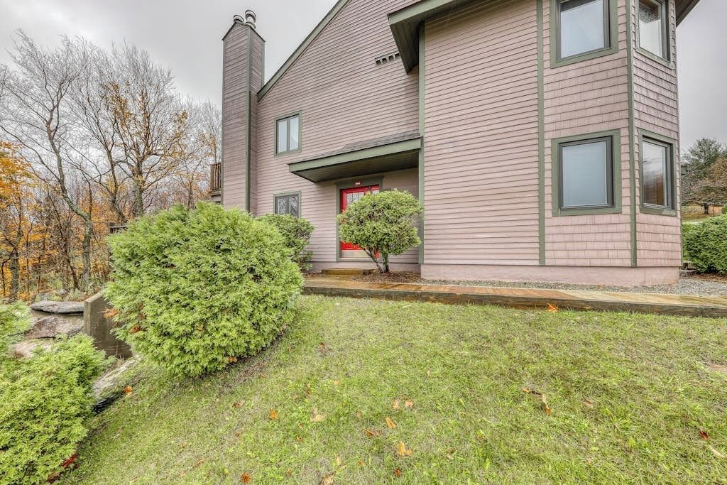 A two-story house with a red door, a chimney, and a well-maintained lawn.