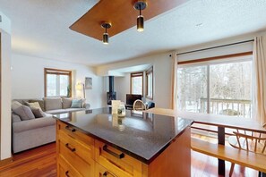 A spacious living area with a large island, wooden furniture, and a view of the outdoors.