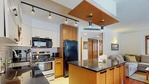 Una cucina moderna con isola centrale, elettrodomestici in acciaio inox e mobili in legno.