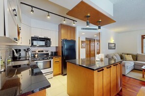 A modern kitchen with a central island, stainless steel appliances, and wooden cabinetry.