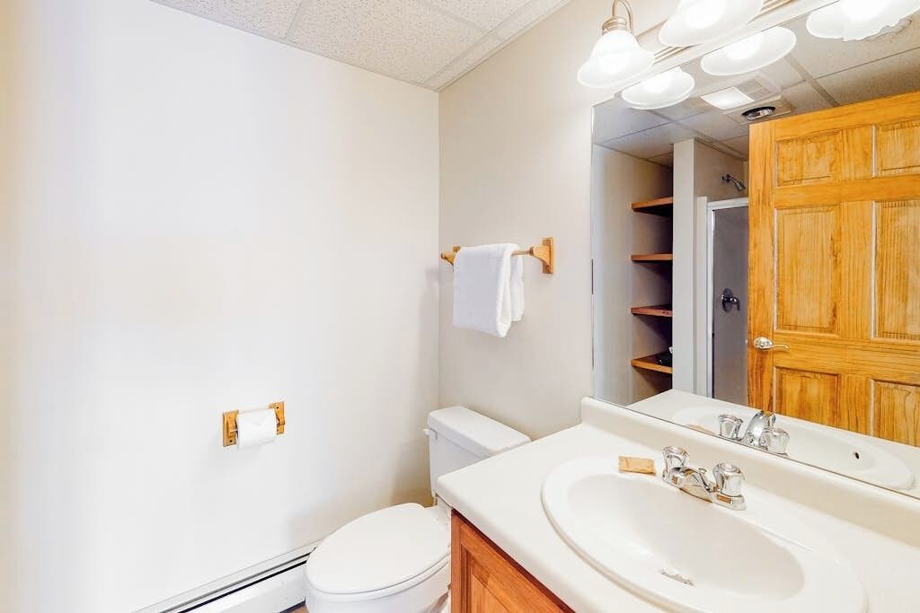 A bathroom with a toilet, sink, mirror, and towel rack.