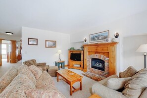 Una sala de estar con chimenea, sofás, una mesa de centro y una televisión.