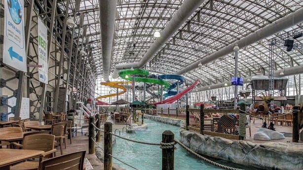 An indoor water park with a large pool, slides, and seating areas.