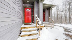 A house with a red door, wooden steps, and a covered porch.