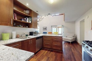 A kitchen with wooden cabinets, a granite countertop, a dishwasher, and a stove. - Mountain view house w/ two fireplaces, BBQ, w/d, jacuzzi, wifi, a/c (Elmore)