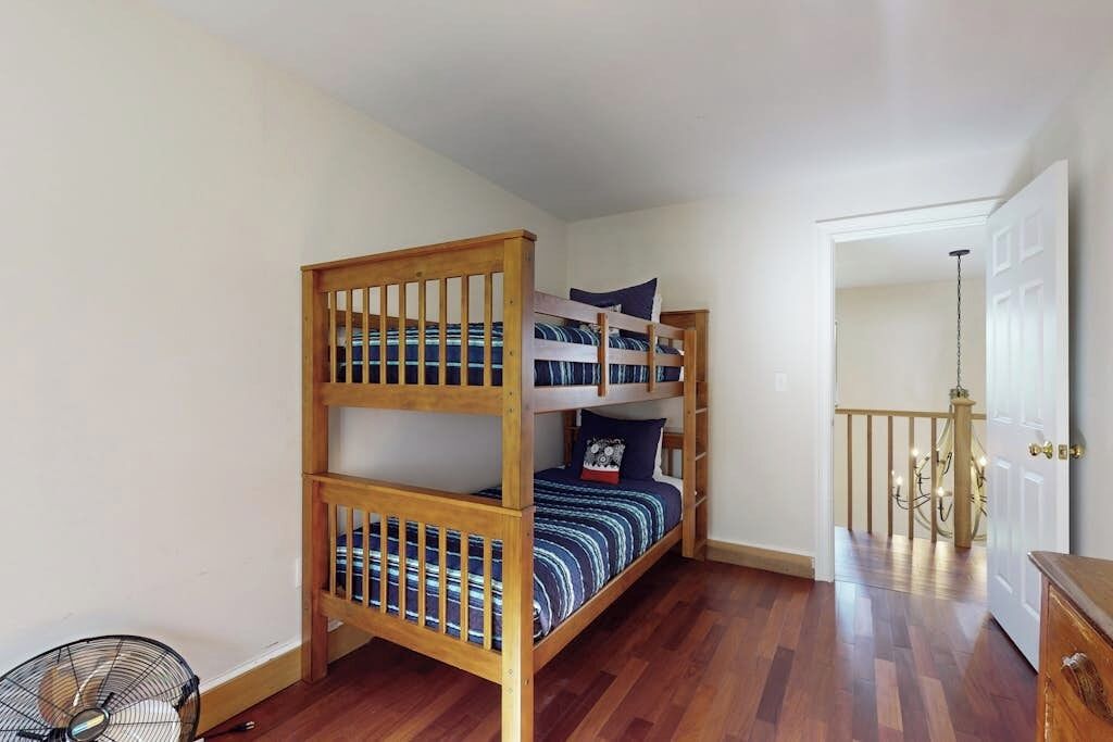 A bunk bed with a wooden frame, a fan, and a door leading to another room.