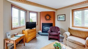 Een woonkamer met een open haard, een televisie, een houten bureau en twee banken.