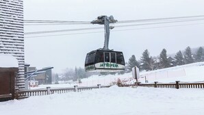 Een kabelbaan met de tekst 'JAY PEAK' hangt boven een besneeuwd landschap.