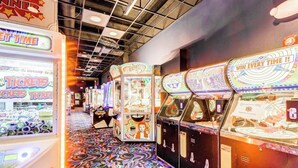 Een rij spelautomaten met ticketinwisseling, een vloer met een patroon en een plafond met zichtbare balken.