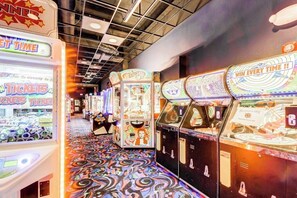 Eine Reihe von Spielautomaten mit Ticket-Lösegeräten, ein gemusterter Boden und eine Decke mit freiliegenden Balken.