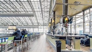 Een binnenzak ruimte met tafels, stoelen, een balie en een groot raam.