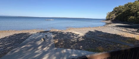 Une vue sur la plage avec une terrasse en bois, un chemin en béton et une clôture en bois.