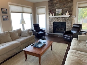 A living room with a stone fireplace, two leather chairs, a sofa, and a coffee table. - Lakeside retreat with grill, fireplace, W/D, AC & sunset views - dog-friendly (Colchester)