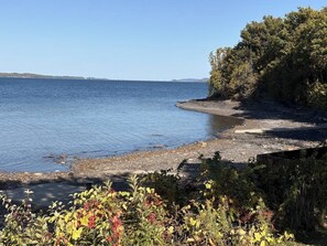 A coastal landscape with a clear view of the sea, a sandy beach, and dense vegetation. - Lakeside retreat with grill, fireplace, W/D, AC & sunset views - dog-friendly (Colchester)