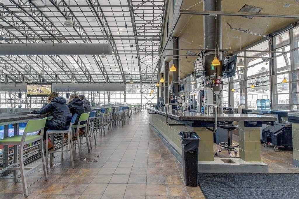 Un vaste espace intérieur doté de hauts plafonds et de grandes fenêtres, aménagé avec des espaces pour s’asseoir et des comptoirs de service.