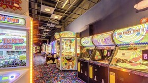 A row of arcade machines with ticket redemption options, a patterned floor, and a ceiling with visible beams.