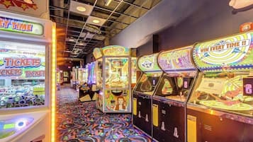 A row of arcade machines with ticket redemption options, a patterned floor, and a ceiling with visible beams.