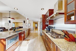 Eine moderne Küche mit Granit Arbeitsplatten, Edelstahlgeräten und Holzschränken.