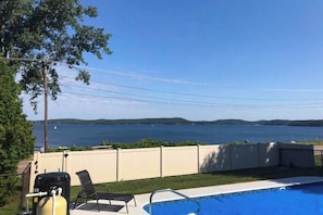 Ein Pool mit Seeblick, ein Grill und ein Stuhl.