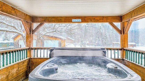 Un bain à remous dans un chalet en bois, avec vue sur un paysage enneigé.
