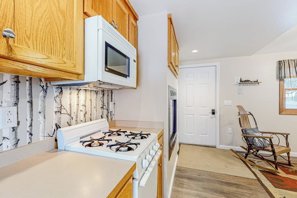 A kitchen with wooden cabinets, a white stove, and a microwave.