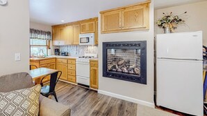 Une cuisine compacte avec des meubles en bois, un four à micro-ondes encastré, une cuisinière et un réfrigérateur.